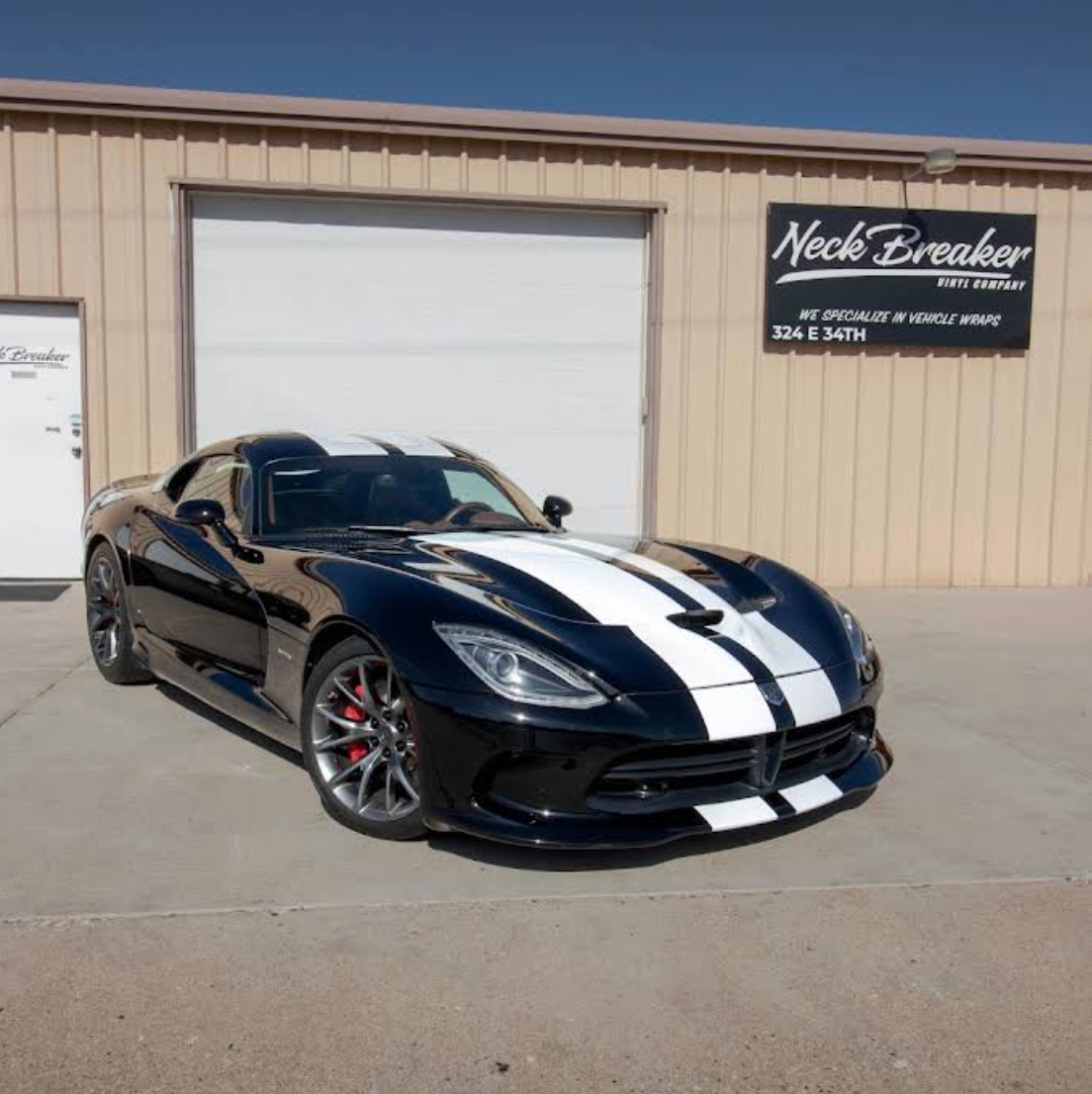 Black sports car with white racing stripes wrapped by Neck Breaker